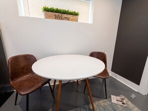 A meeting room with a round table and two brown chairs, a 'Welcome' sign above, and a window with blinds. - Private 1BR King Suite • Near Downtown Nashville (Nashville)