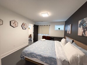 A modern bedroom with a large bed, a desk, and a chair. There are two framed artworks on the wall. - Private 1BR King Suite • Near Downtown Nashville (Nashville)