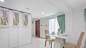Zona de menjador amb una taula preparada per a dues persones, cadires, una planta en test i obra d'art a la paret.
