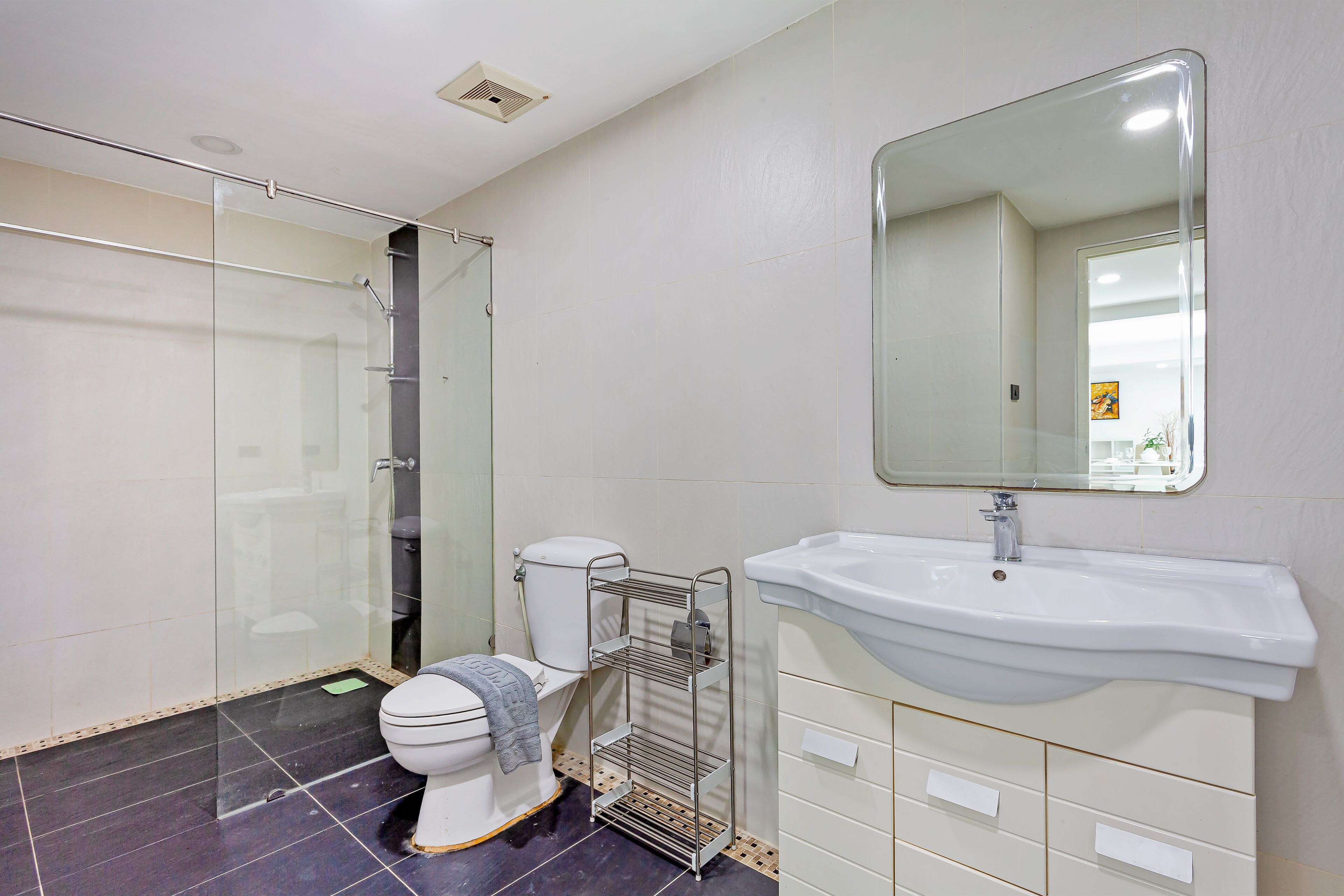 A bathroom with a toilet, a sink, a shower, and a mirror.