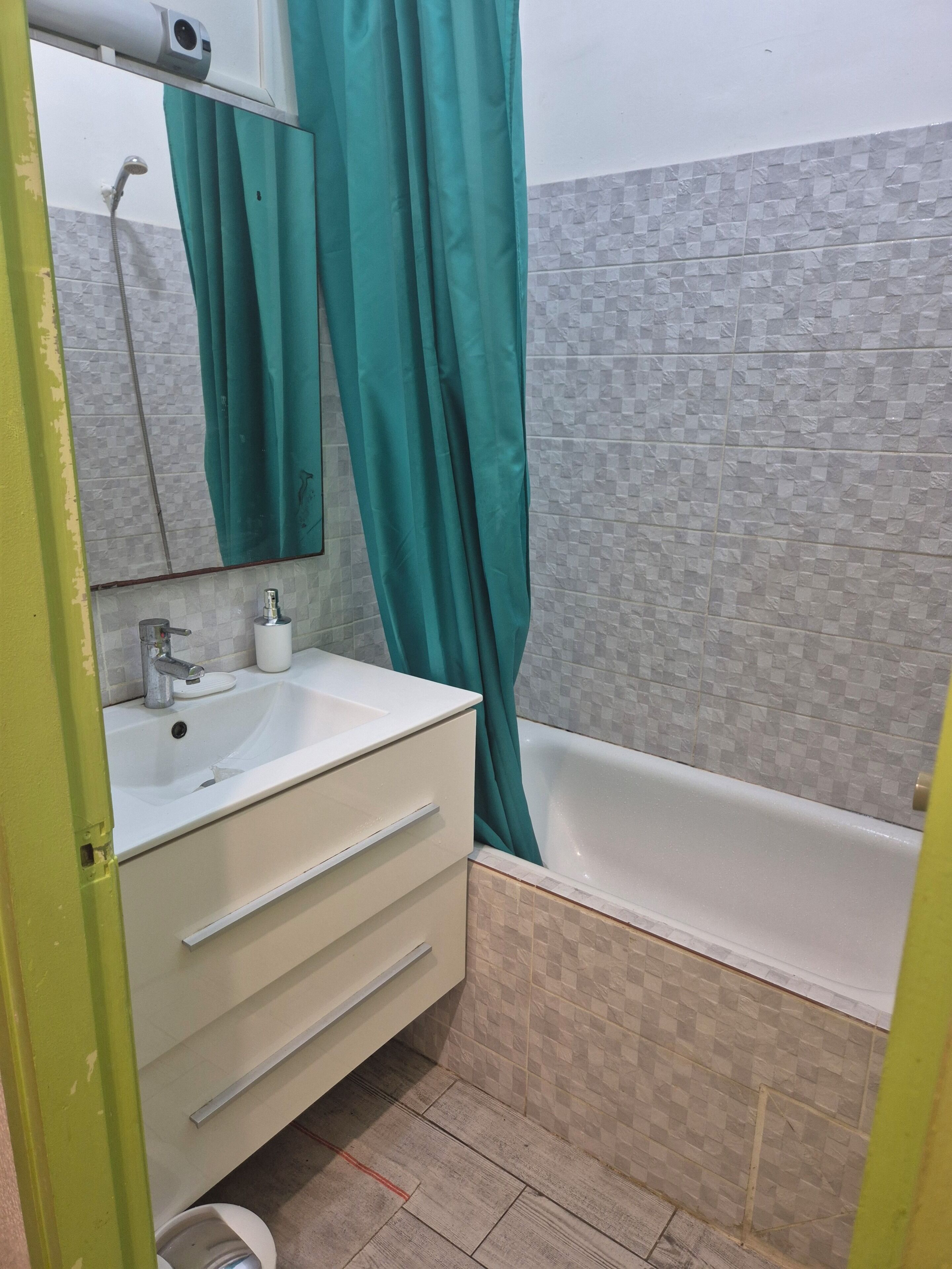 A bathroom with a white sink, a mirror, a green shower curtain, and a bathtub.