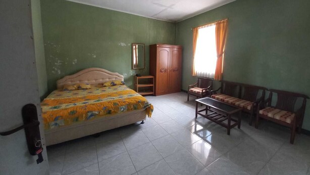 A room with a bed, a wooden wardrobe, a small table, and a sofa. - Rehat at Linggarjati - Kuningan (Cilimus)