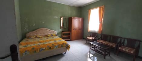 Una habitación con una cama, un armario de madera, una mesita pequeña y un sofá.