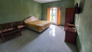 A bedroom with a bed, a wooden bench, a TV, and a window with curtains.