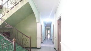 A corridor with a staircase leading to an upper floor, flanked by walls with decorative moldings. - Rehat at Linggarjati - Kuningan (Cilimus)