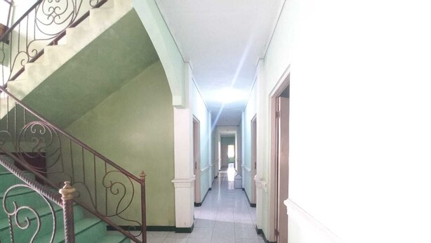 A corridor with a staircase leading to an upper floor, flanked by walls with decorative moldings.