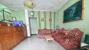 A reception area with a wooden desk, a sofa, and a television.