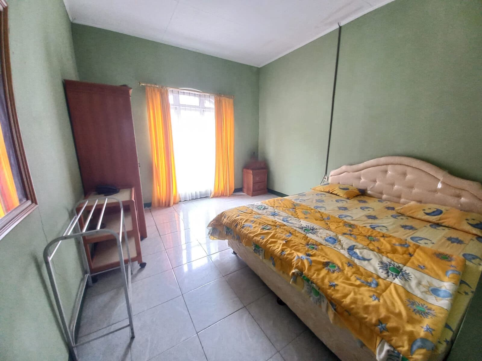 A bedroom with a bed, a desk, and a wardrobe.