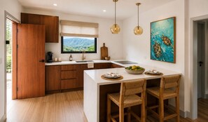 Une cuisine moderne avec des meubles en bois, un îlot central doté de sièges, une fenêtre offrant une belle vue et un éclairage suspendu.