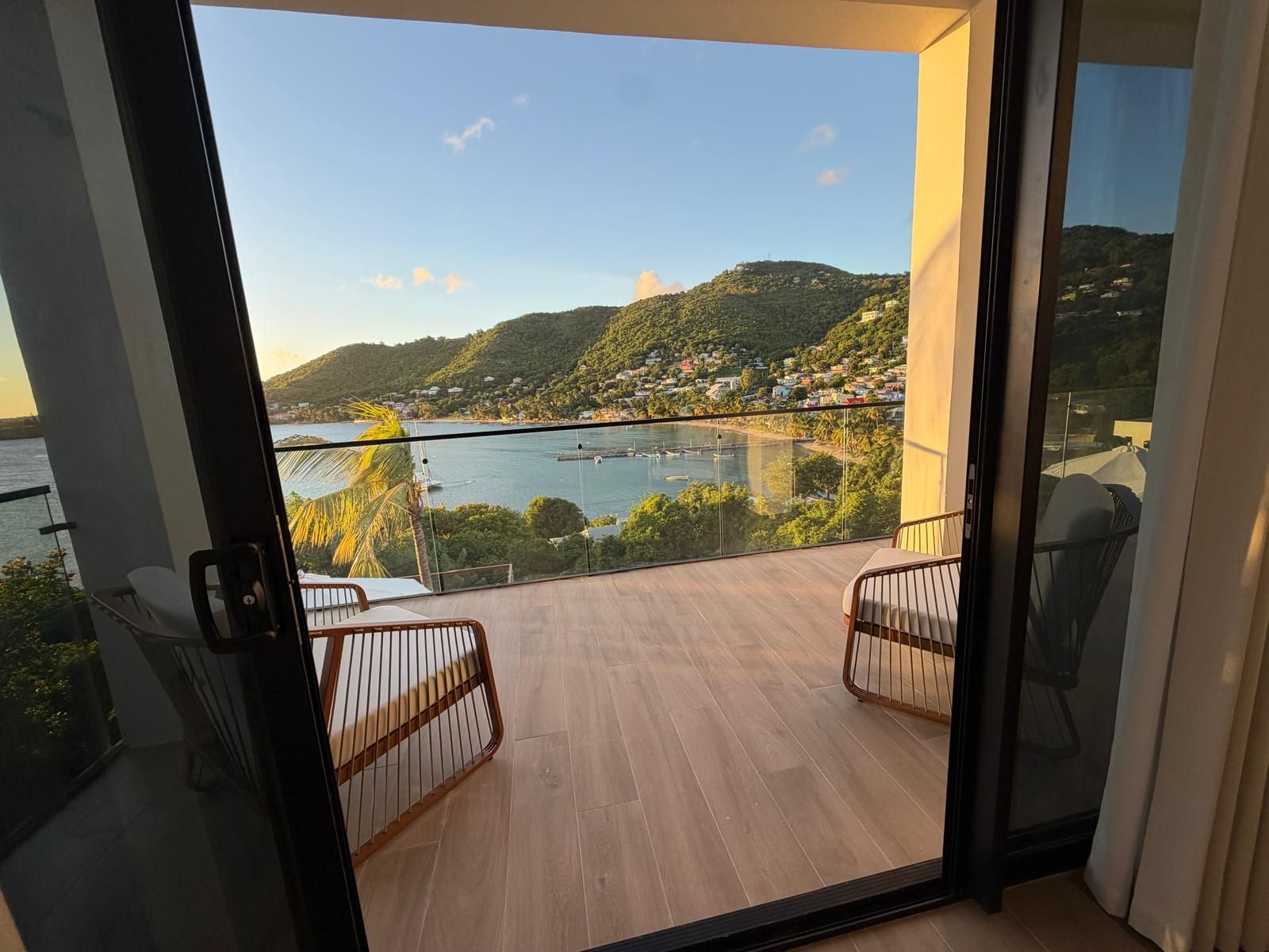 A balcony with a view of a coastal landscape, including hills and a body of water.