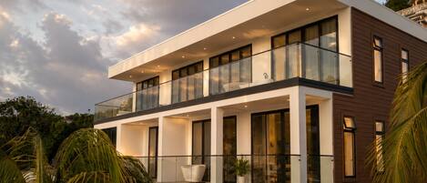 Un bâtiment moderne à deux étages, doté de grandes fenêtres, d’un balcon et d’un toit plat.