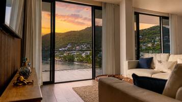 A modern living room with a sofa, a coffee table, and a view of a hillside town through large glass doors.