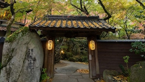 Ein traditionelles japanisches Torii-Tor führt in einen friedlichen Garten mit einem Kiesweg.