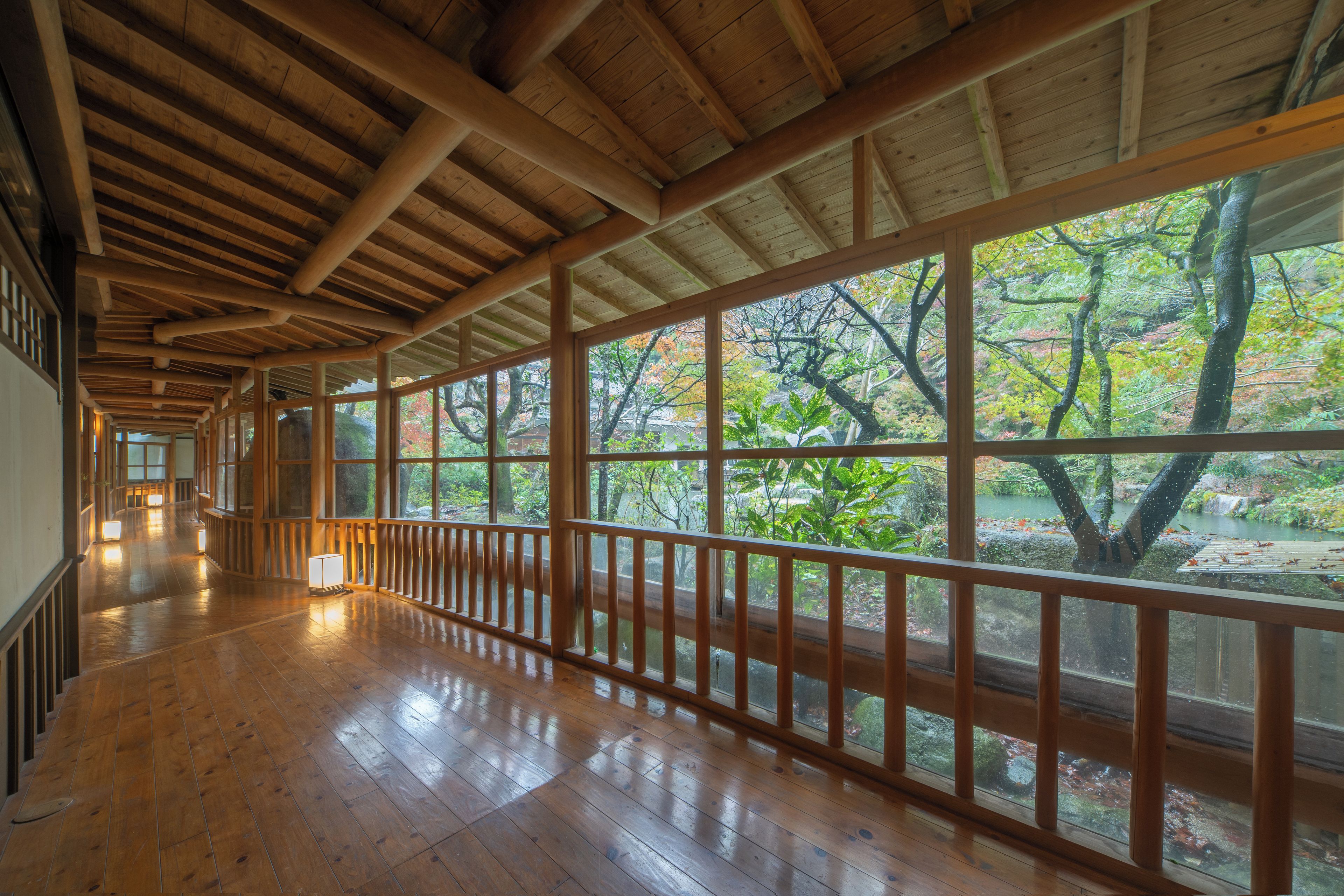 A corridor with wooden flooring and large windows.