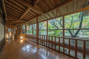 A corridor with wooden flooring and large windows.