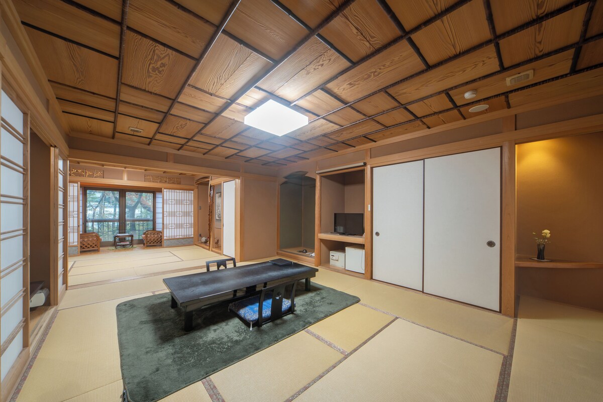 A traditional Japanese room with tatami flooring, a low table, sliding doors, and a television.