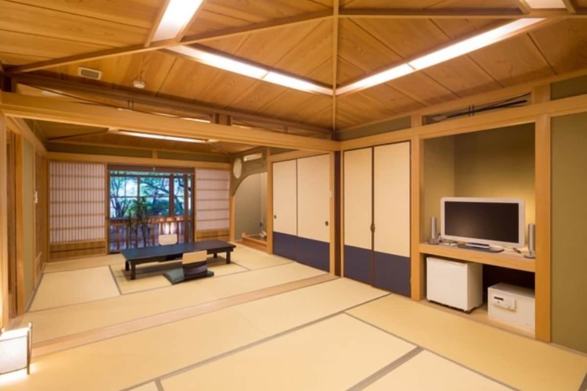 A tatami mat room with a tatami mat table, a television, and a cabinet.