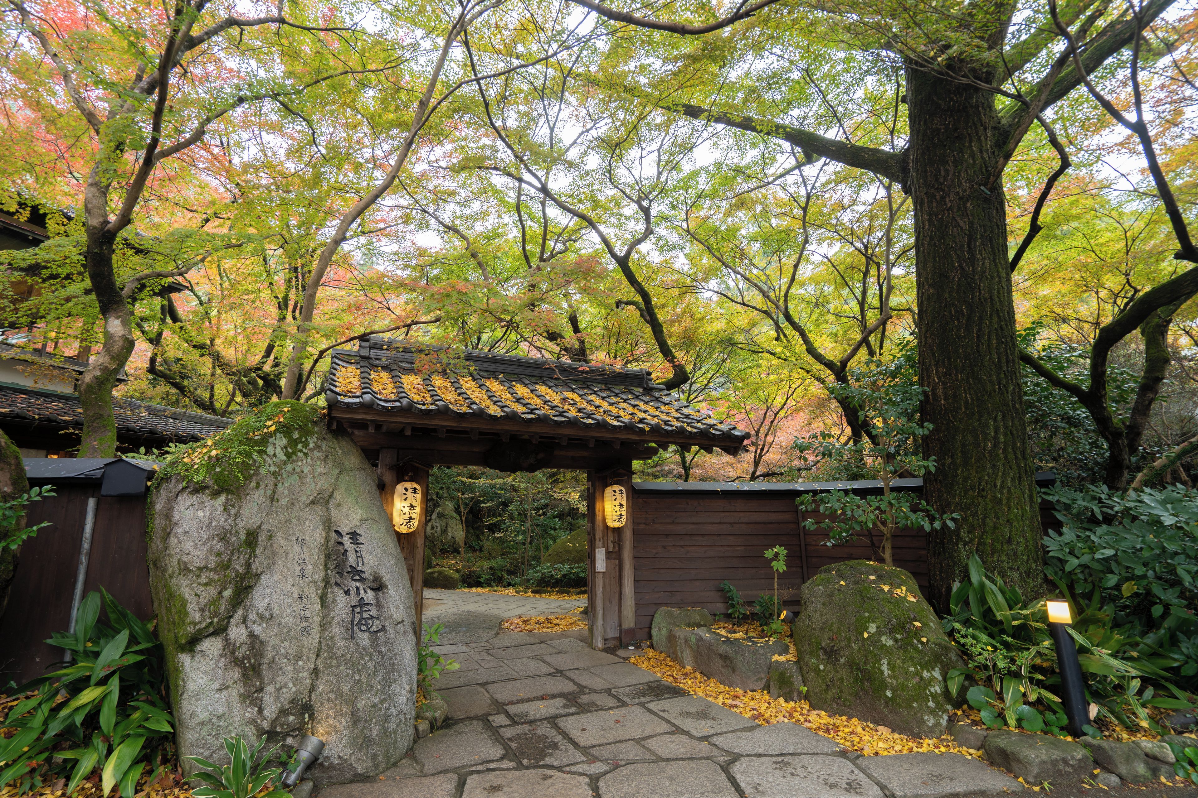 Ein traditioneller japanischer Garten mit einem Kiesweg, der zu einem hölzernen Tor führt.