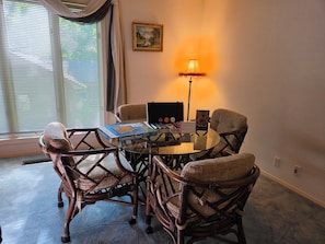 A room with a round glass table surrounded by four wicker chairs, a lamp, and a painting on the wall. - West Gate Retreat 3 bedroom home near Desoto Golf Club in Hot Springs Village (Hot Springs)