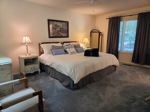 A bedroom with a bed, bedside tables, a lamp, a picture on the wall, and a window with curtains.