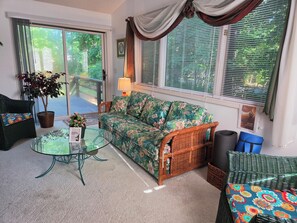 A furnished living room with a sofa, a glass coffee table, a wicker chair, and a potted plant. - West Gate Retreat 3 bedroom home near Desoto Golf Club in Hot Springs Village (Hot Springs)