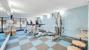 A gym with cardio machines, weight benches, and a mirrored wall. - Carolinian Beach Resort 0830 (Myrtle Beach)