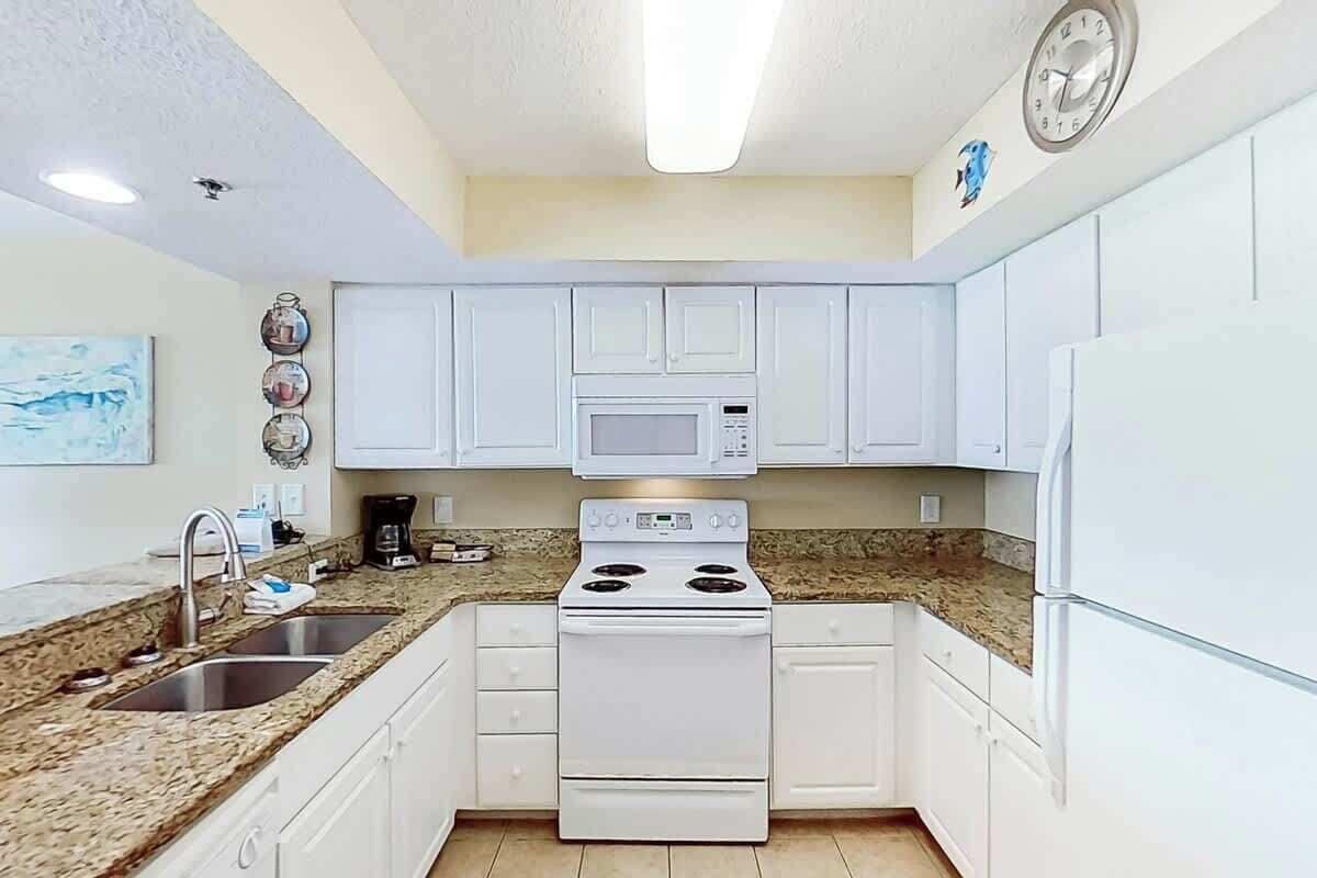 A kitchen with white cabinets, a microwave, a stove, and a refrigerator.