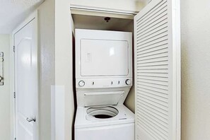 Een kleine wasruimte met een verticaal gestapelde wasmachine en droger.
