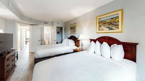 Ein Hotelzimmer mit zwei Betten, einem Fernseher, einem Schminktisch und einem Bild an der Wand.