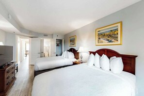 A hotel room with two beds, a television, a dresser, and a painting on the wall. - Carolinian Beach Resort 0831 (Myrtle Beach)
