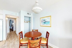 A dining area with a round table and chairs, a ceiling light, and a framed picture on the wall. - Carolinian Beach Resort 0831 (Myrtle Beach)