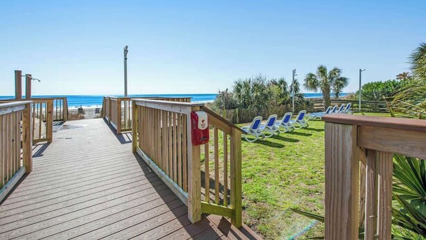 A wooden boardwalk leading to beach chairs and palm trees. - Oceanview Penthouse 2134 (Myrtle Beach)
