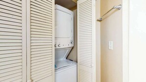 A laundry room with a stacked washer and dryer, a towel rack, and a door with a handle. - Oceanview Penthouse 2134 (Myrtle Beach)