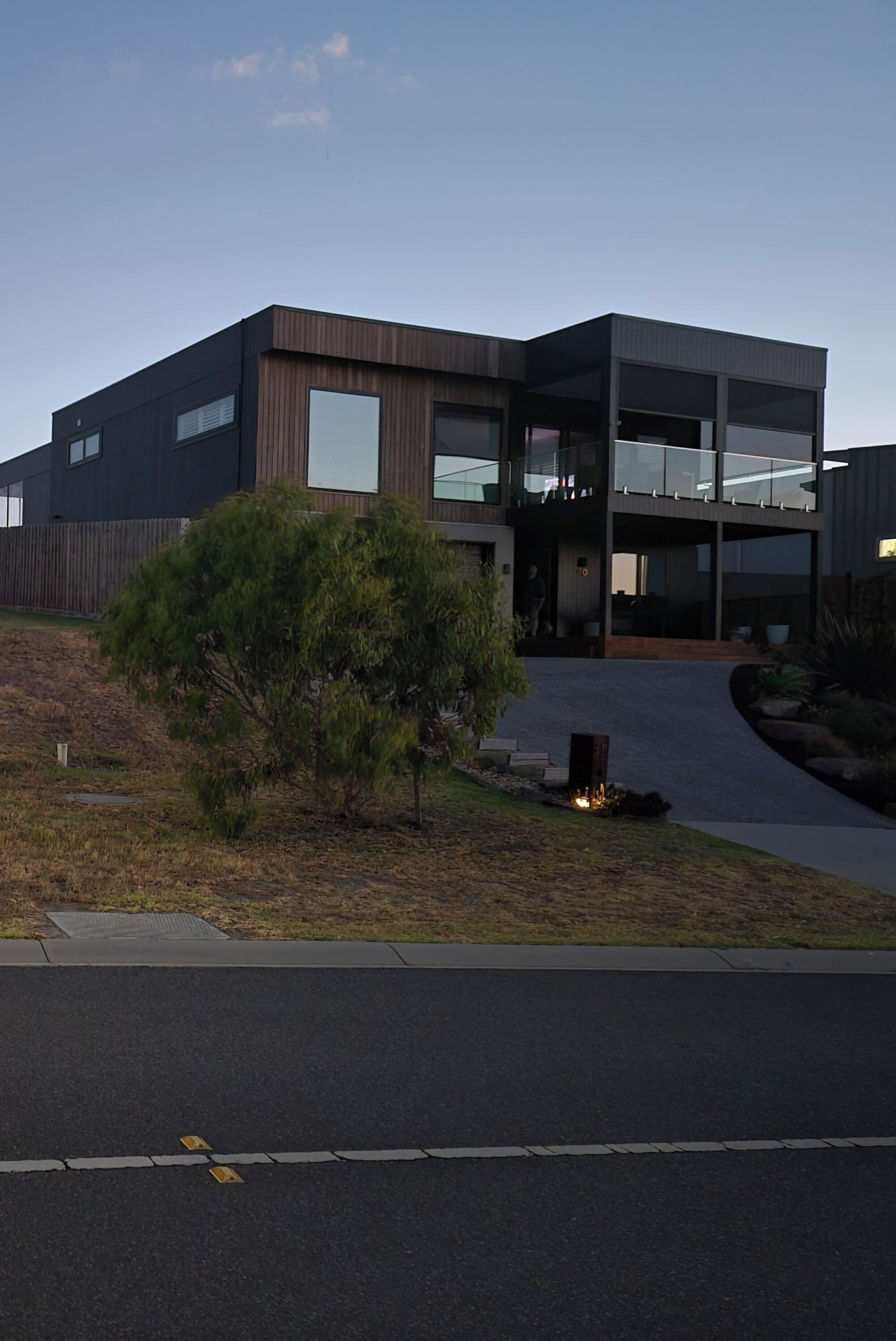 A modern two-story building with a flat roof, large windows, and a covered entrance.