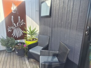 A patio with wicker furniture, potted plants, and a decorative wall panel.