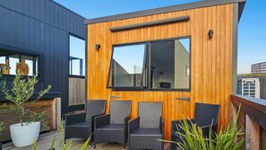 A modern outdoor seating area with wicker chairs and a wooden wall.