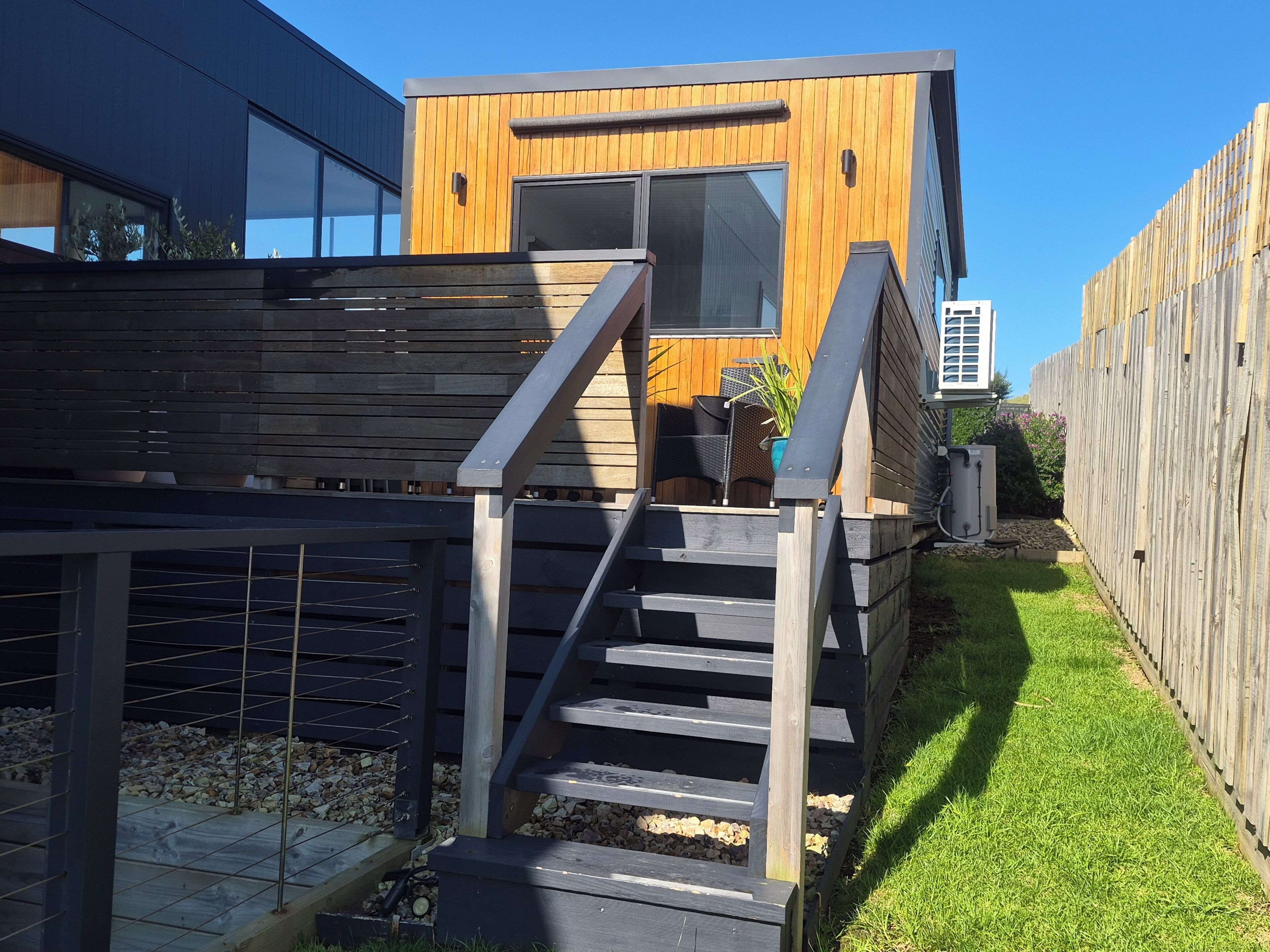 A modern wooden building with a staircase leading to a deck area.
