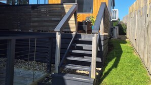 A modern wooden building with a staircase leading to a deck area.