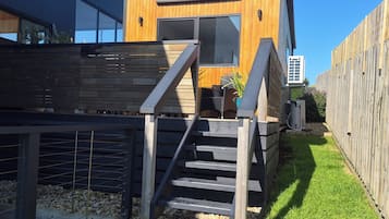 A modern wooden building with a staircase leading to a deck area.