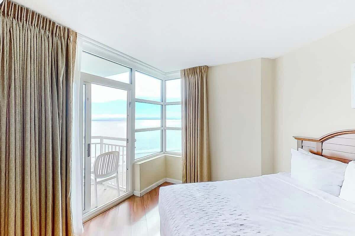 Une chambre d’hôtel avec une grande fenêtre, un lit et une vue sur la mer.