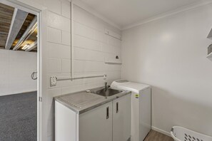 Ein kleiner Hauswirtschaftsraum mit Waschmaschine, Spüle und Wäscheständer.