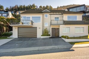 Ein zweigeschossiges Haus mit Garage, Balkon und Auffahrt.