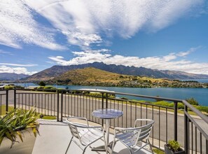 A balcony with a table and chairs overlooking a lake and mountains. - Panorama Point - Amazing Views & Location (Queenstown)