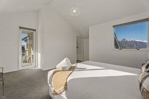 Ein Schlafzimmer mit einem großen Bett, einem Fenster mit Blick auf die Berge und einer Tür, die auf einen Balkon führt.