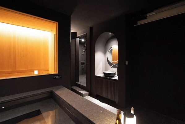 Un baño moderno con tocador de madera, un lavabo con espejo y zona de ducha.