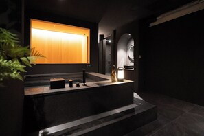 Un baño moderno con un espejo grande, un lavabo y una botella de alcohol.