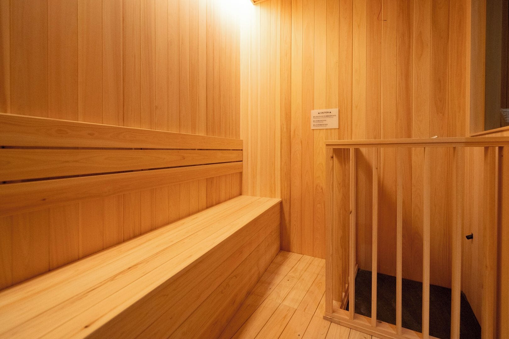 Una sauna de madera con bancos y un letrero de precaución.