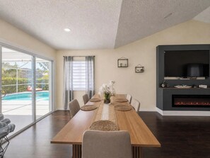 A dining area with a long wooden table, chairs, and a central vase with flowers. - Heated Pool No Extra Fee ! firepit| Game Room (Palm Coast)