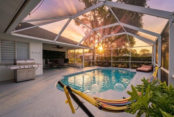 An outdoor swimming pool with a covered patio area, a grill, and a dining table. - Heated Pool No Extra Fee ! firepit| Game Room (Palm Coast)