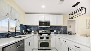 A modern kitchen with white cabinets, a stainless steel range, and a blue-tiled backsplash. - Heated Pool No Extra Fee ! firepit| Game Room (Palm Coast)